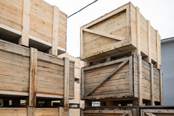 A stack of huge wooden crates in a storage area. Big boxes of goods in an open-air warehouse awaiting transportation. Logistics and distribution concept